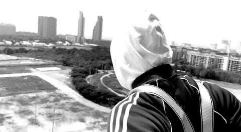 Masked figure in a white hood overlooking a city landscape.